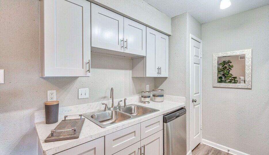 a kitchen with white cabinets and stainless steel appliances at The Del Sol
